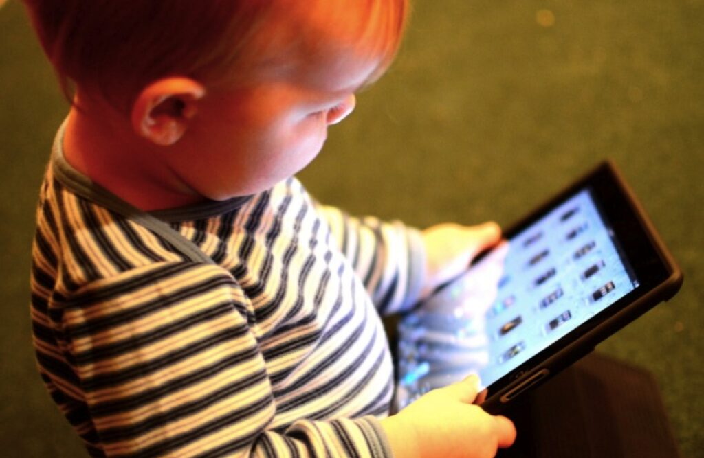 Niño utilizando una tableta con supervisión familiar para fomentar un uso saludable de las pantallas durante la infancia.